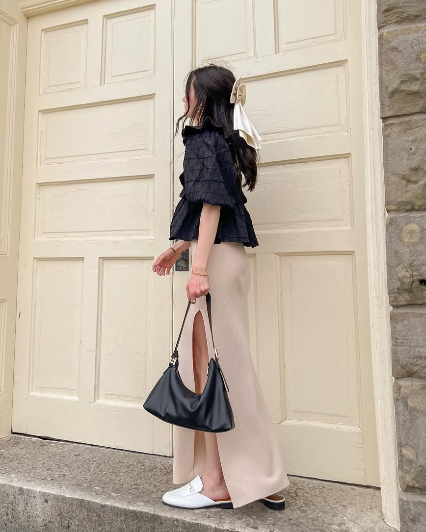 Side of a woman wearing a black blouse standing on steps in front of a large door.