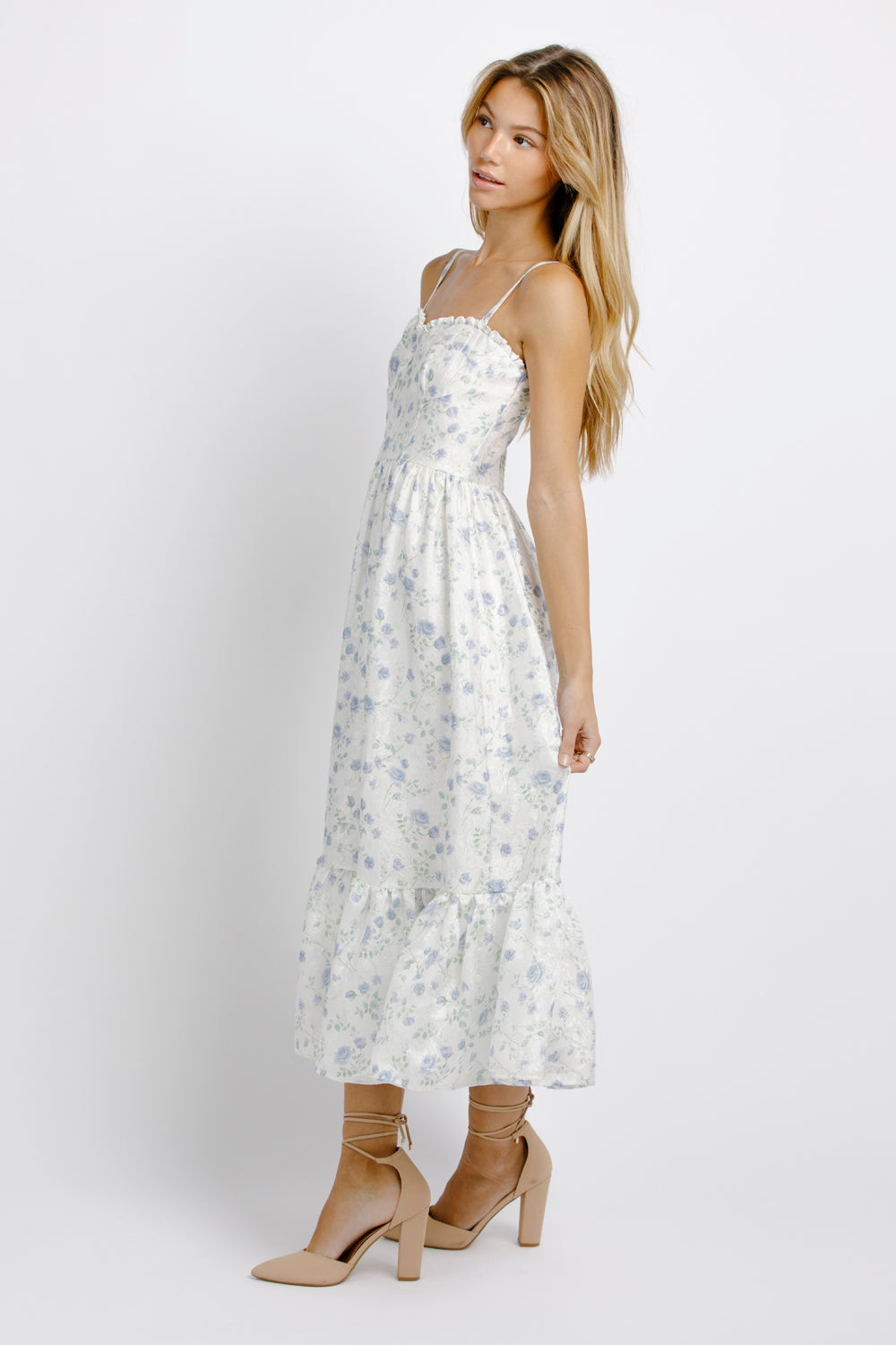 Side view of a woman wearing a white and blue floral dress on a plain background