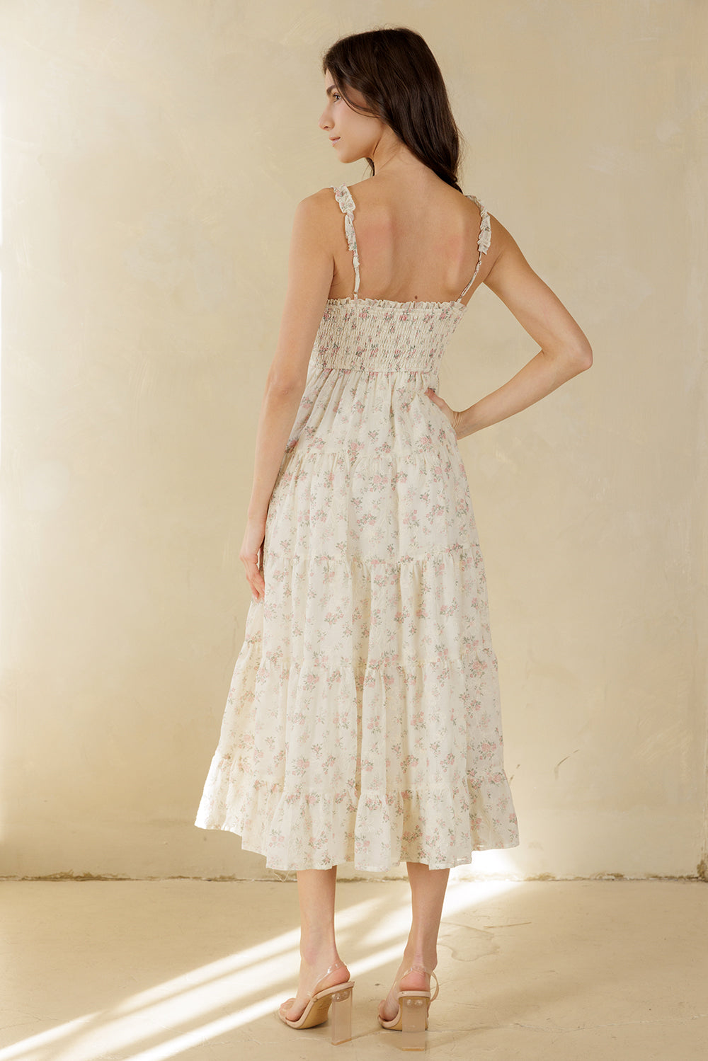 Back view of a woman wearing a floral dress against a plain background