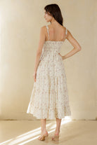 Back view of a woman wearing a floral dress against a plain background