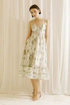 Woman wearing a green and blue tie dye effect dress standing against a plain background