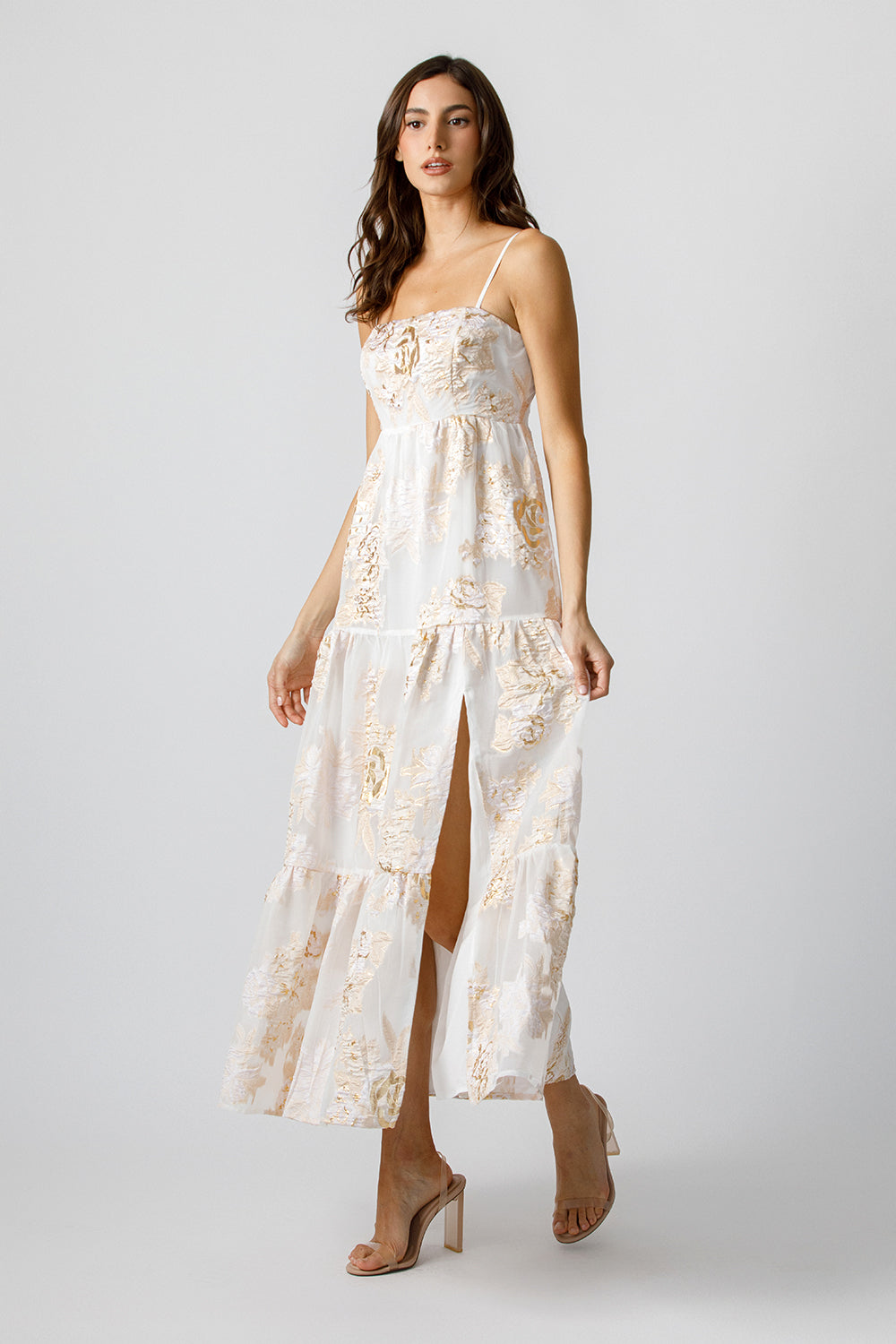 Woman wearing a white floral dress with a slit on a white background