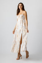 Woman wearing a white floral dress with a slit on a white background