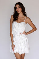 Woman wearing a white layered mini dress against a plain background