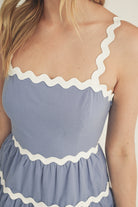 Blue dress with white trim on a plain background