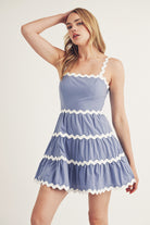 Model wearing a light blue dress with white trim on a plain background