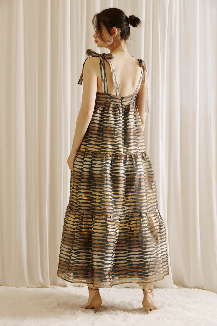Back view of a woman wearing a boho maxi dress with striped pattern, featuring an empire waist, and self-tie straps.