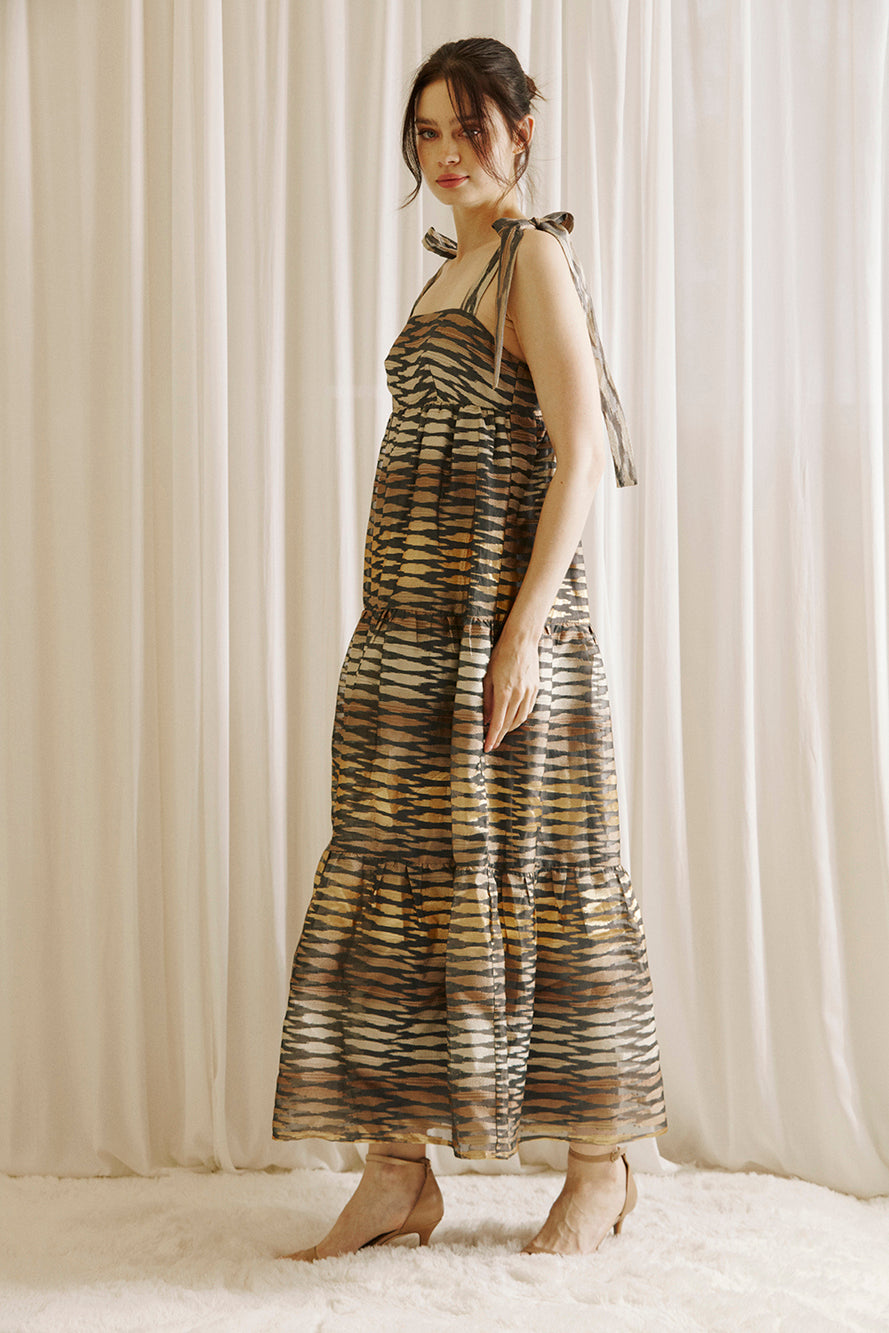 A model wearing a boho maxi dress with striped pattern, featuring a straight neckline, empire waist, and self-tie straps.