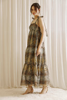 A model wearing a boho maxi dress with striped pattern, featuring a straight neckline, empire waist, and self-tie straps.