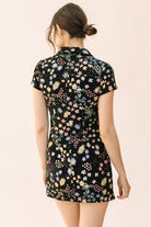 Back view of a woman wearing a black  dress with floral pattern on a beige background