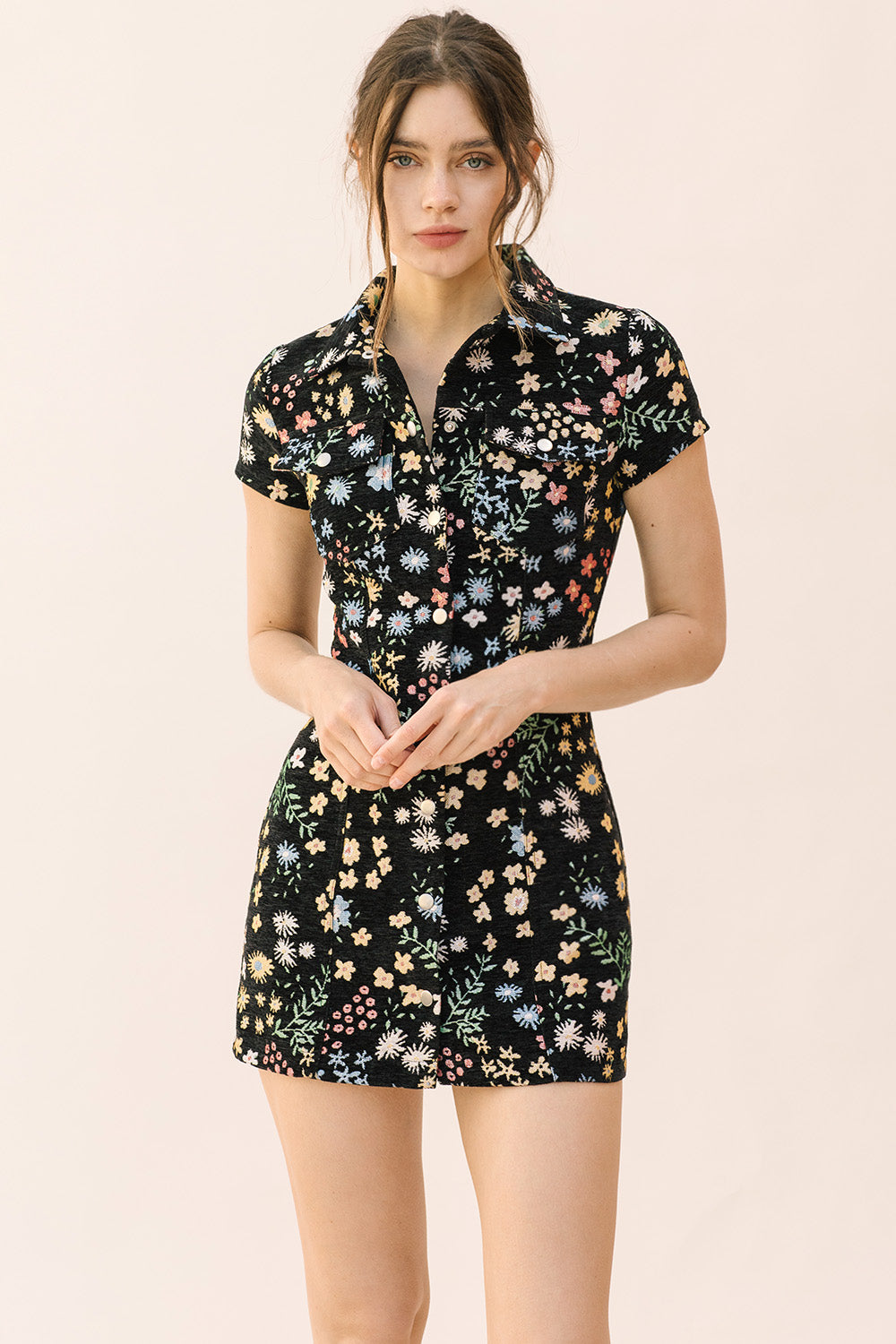 Woman wearing a black bodycon dress with floral pattern on a beige background