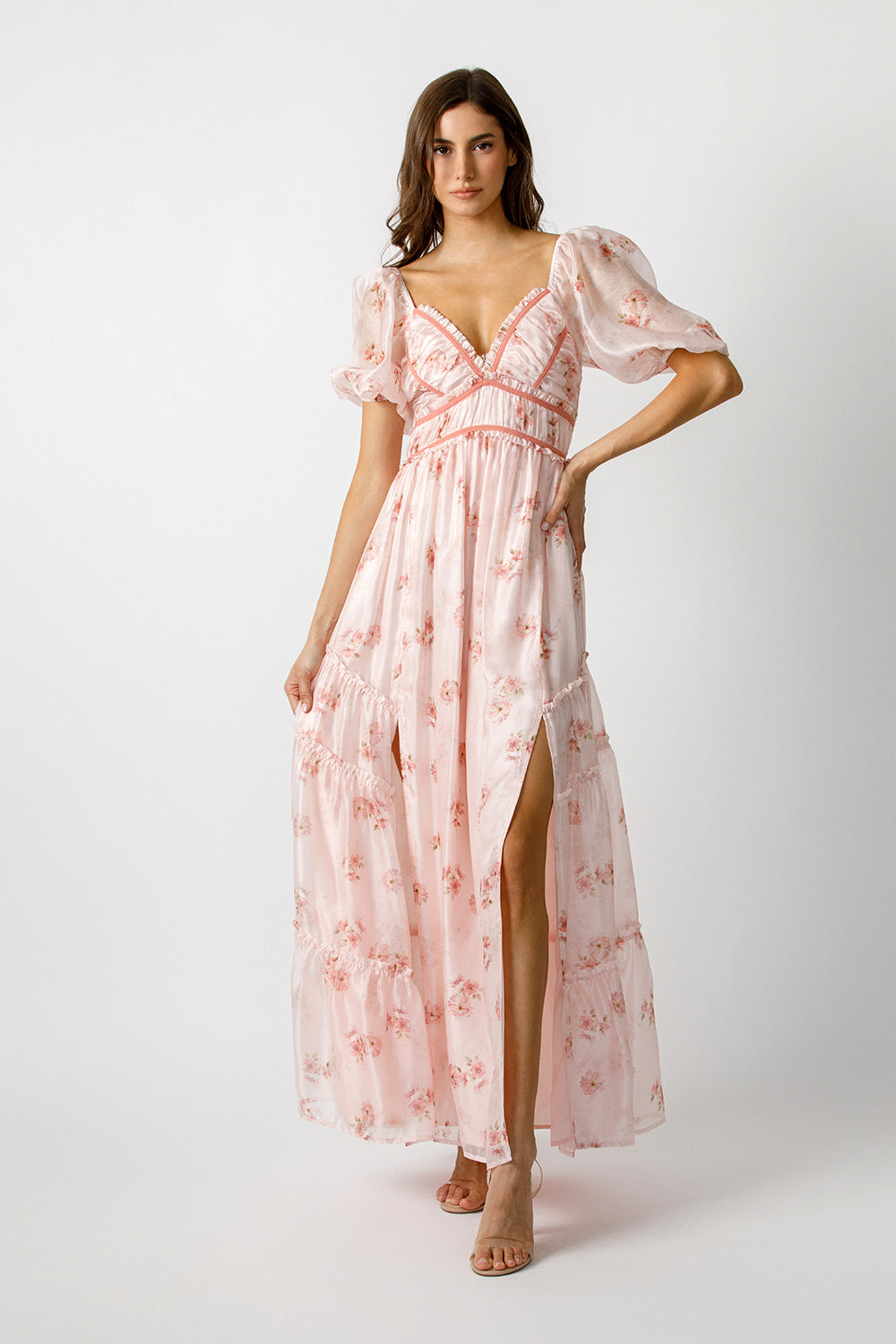 Woman wearing a pink floral maxi dress on a white background
