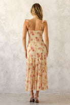 A woman viewed from behind wearing a floral dress with a plain background