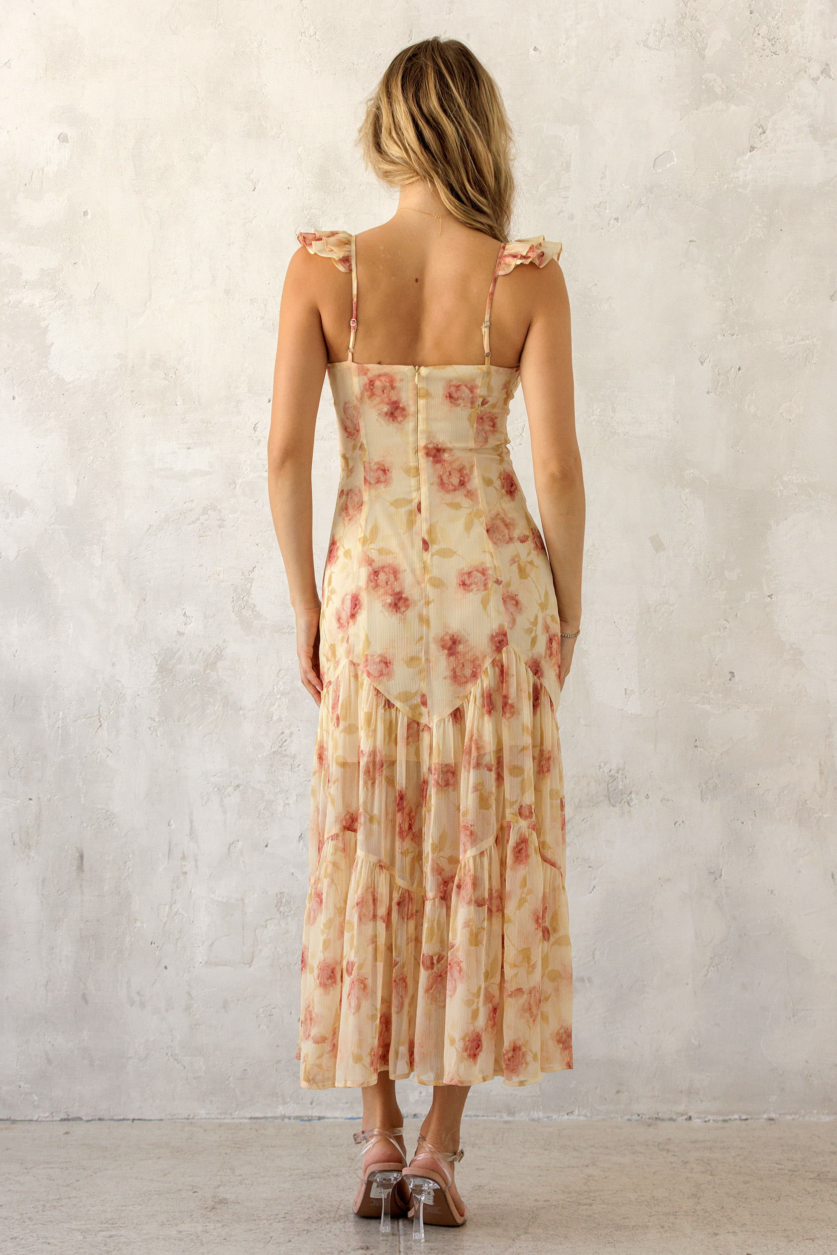 A woman viewed from behind wearing a floral dress with a plain background