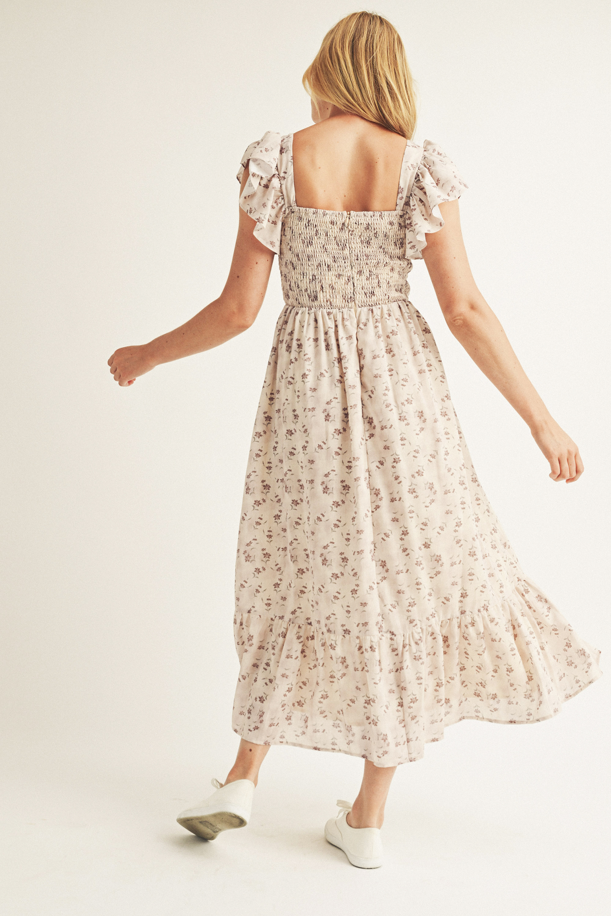 Back view of a woman wearing a floral print midi dress with a smocked bodice and back invisible zipper.