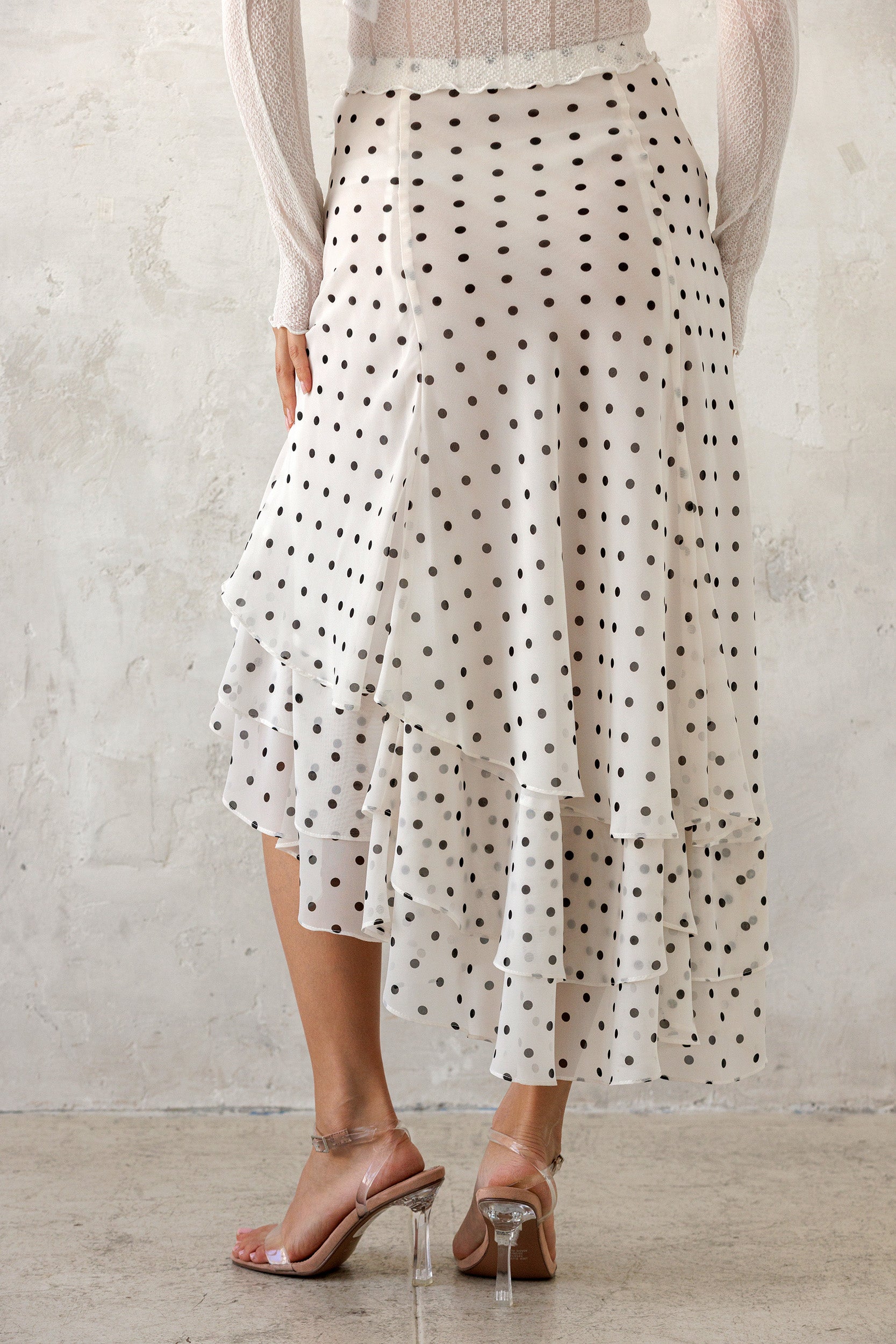 Person wearing a polka dot skirt with a plain background