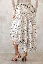 Person wearing a polka dot skirt with a plain background