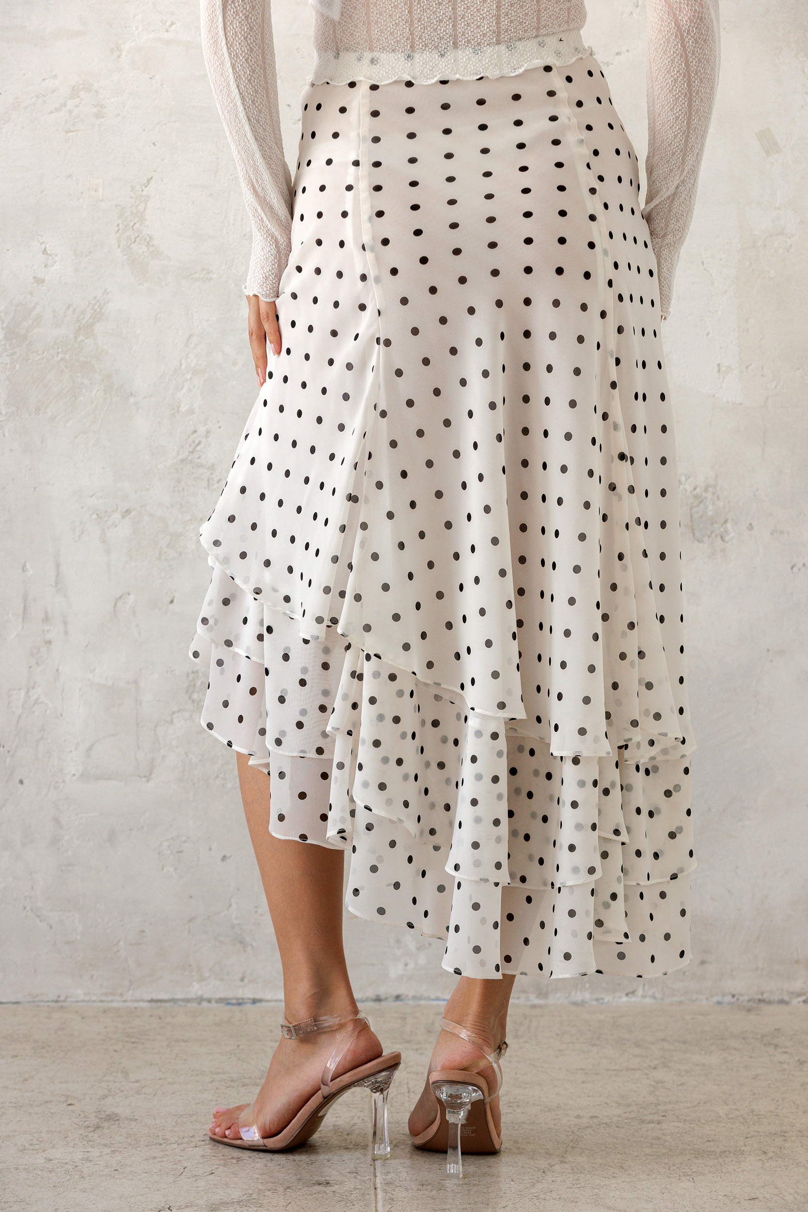 Person wearing a polka dot skirt with a plain background
