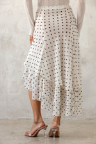 Person wearing a polka dot skirt with a plain background