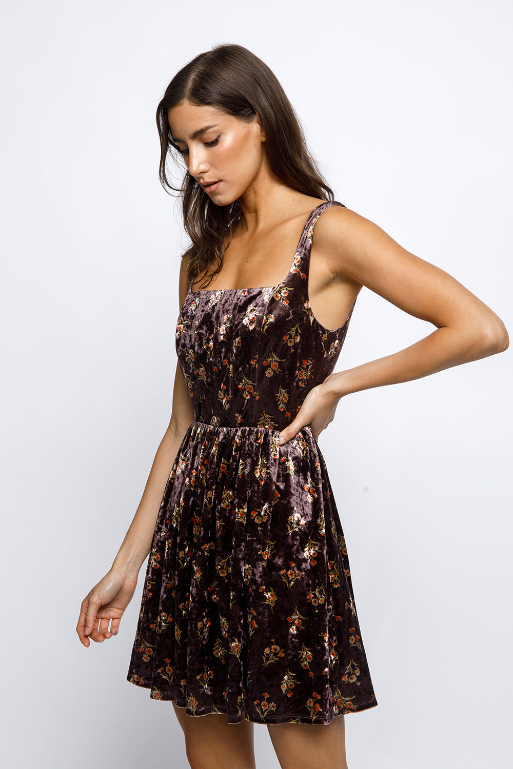 Woman wearing a brown floral mini dress against a white background