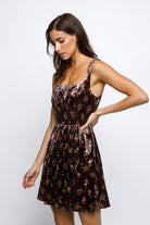 Woman wearing a brown floral mini dress against a white background