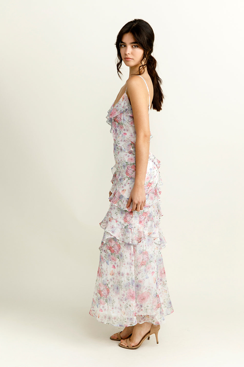 Side view of a woman wearing a purple floral dress on a white background