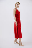 Side view of a woman wearing a red dress with beige shoes on a white background