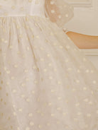 Cream polka dot dress against a neutral wall