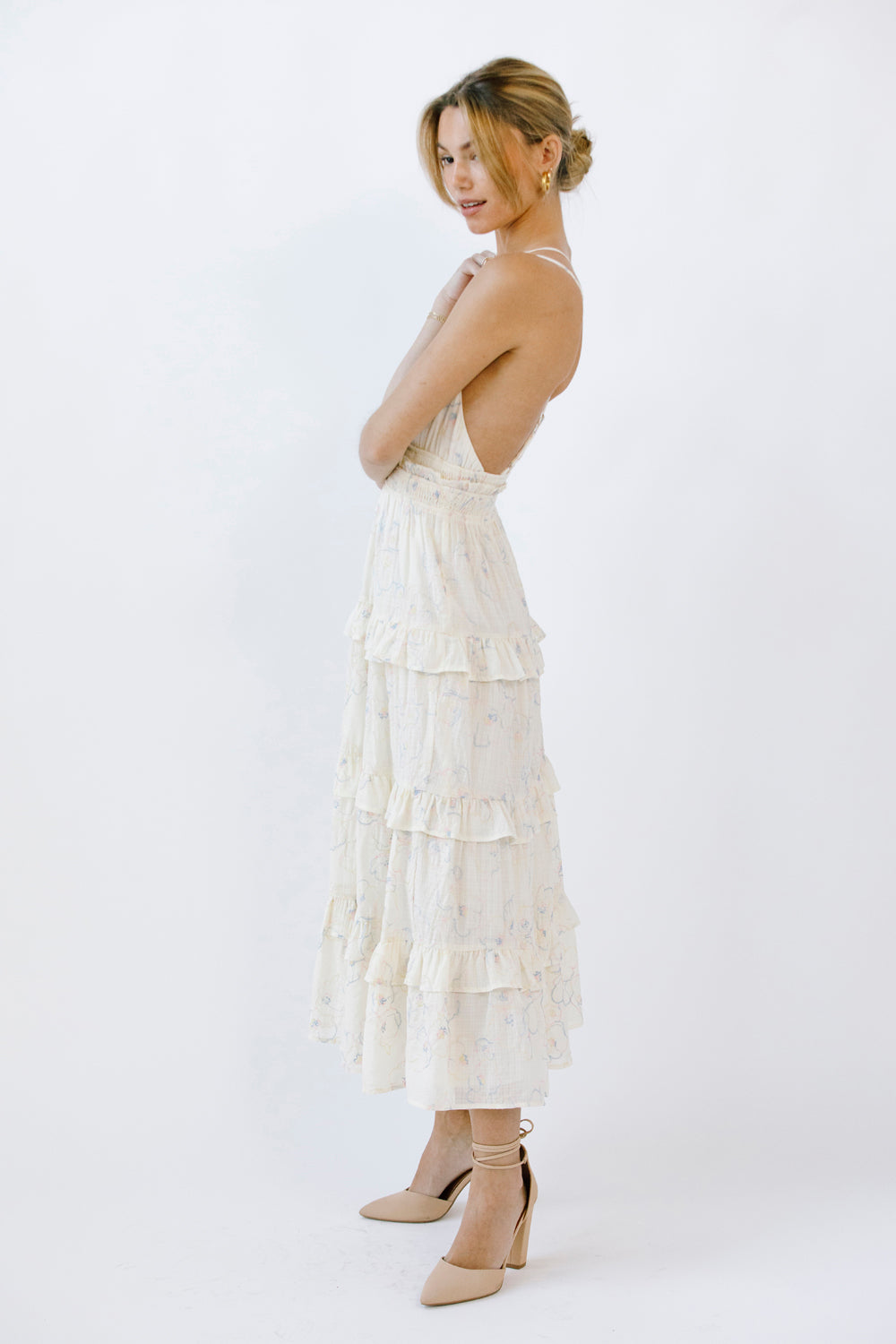 Woman wearing a midi dress with ruffled layers on a white background