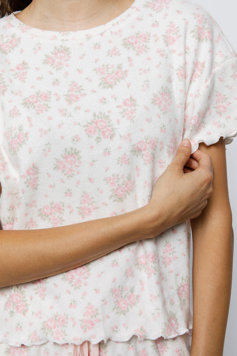 Close-up of a person wearing a white floral pajama top with a plain background