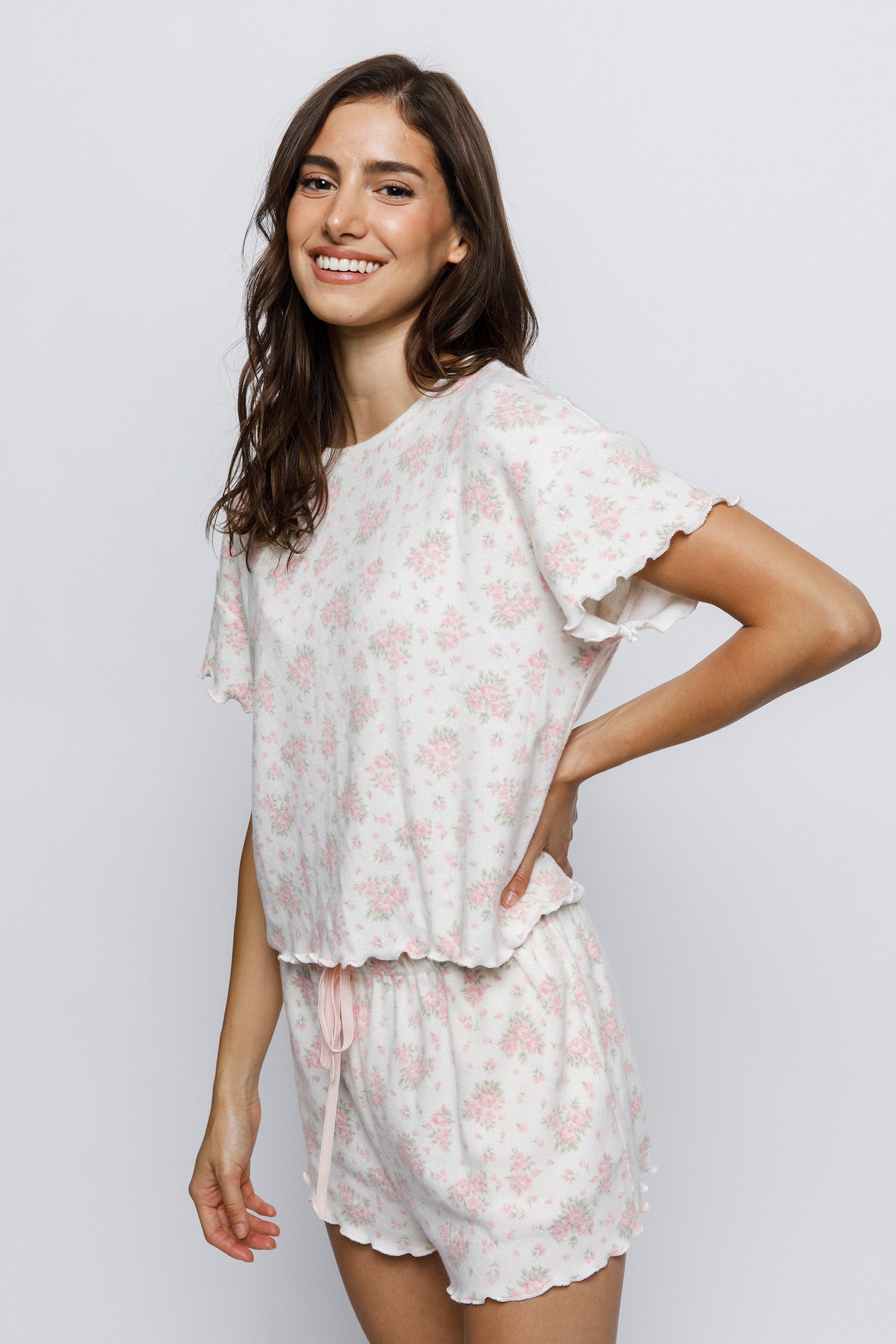 Woman wearing a white floral pajama set on a plain background