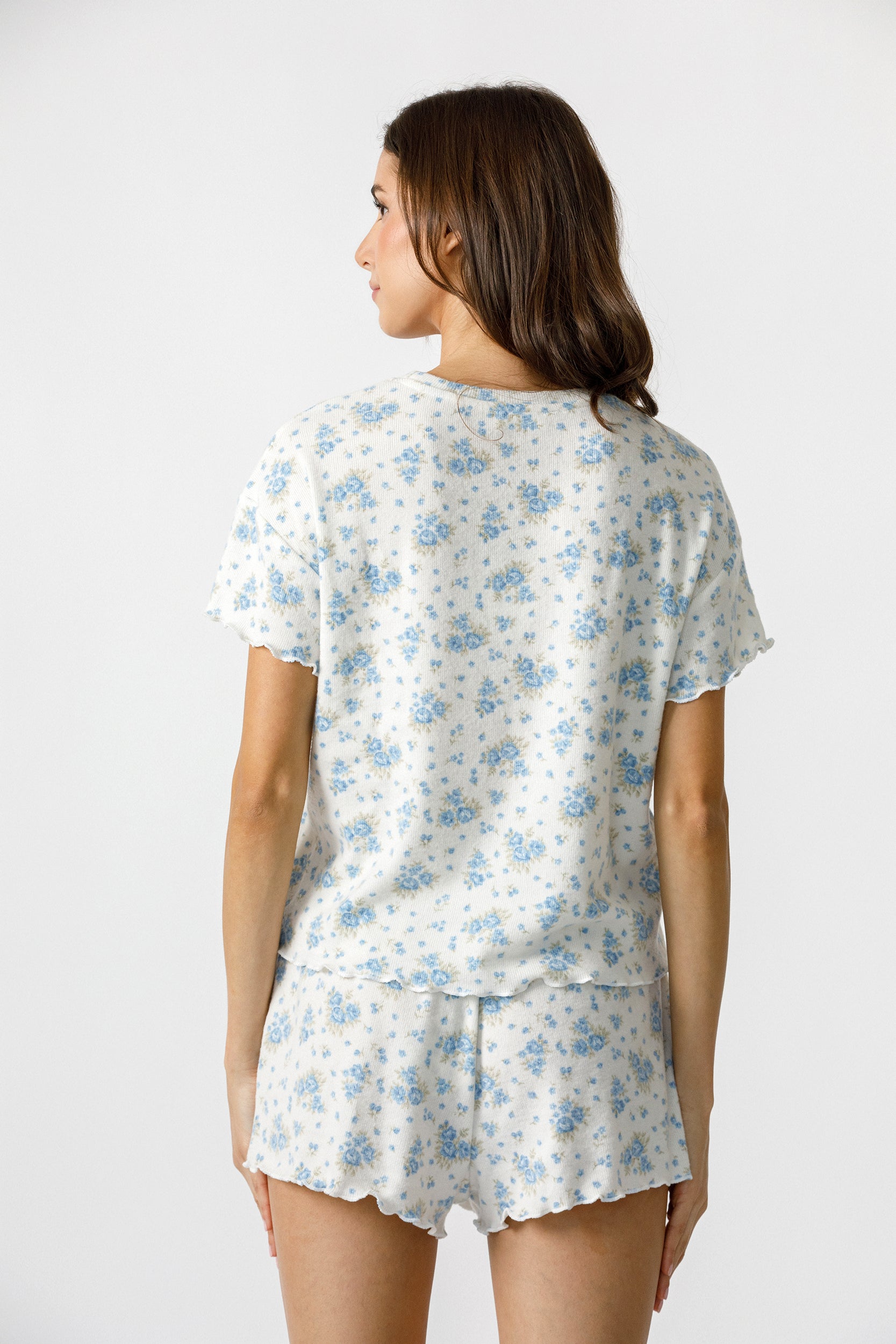 Back view of a woman wearing a floral pajama set on a white background