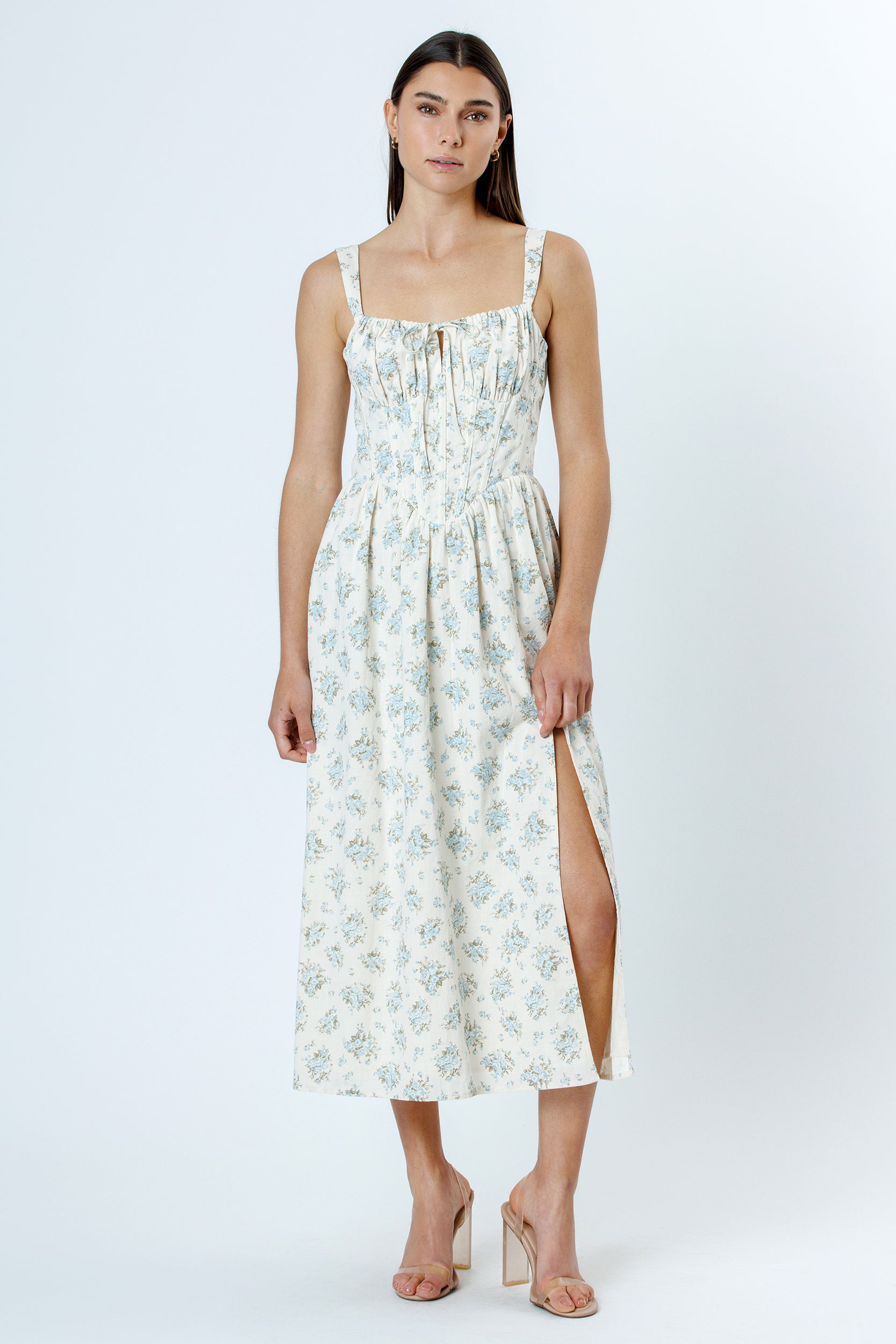 Woman wearing a floral dress with a slit on a white background