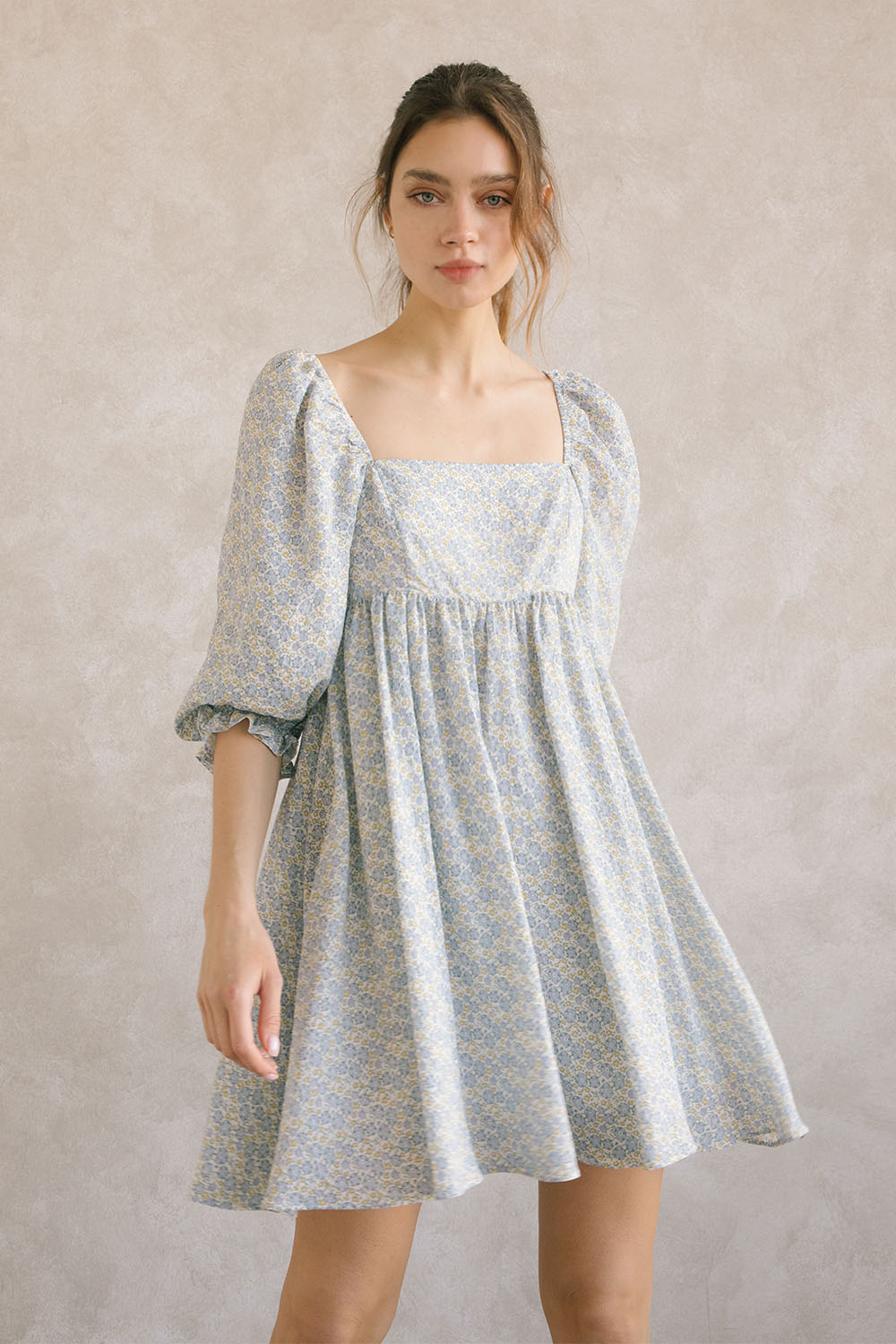 Woman wearing a blue floral dress against a plain background