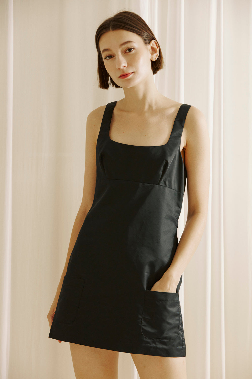 Woman wearing a black dress against a light background