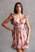 Woman wearing a pink floral dress against a gray background