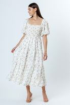 Woman wearing an ivory with pink rosebuds and flower jacquard print midi dress on a white background