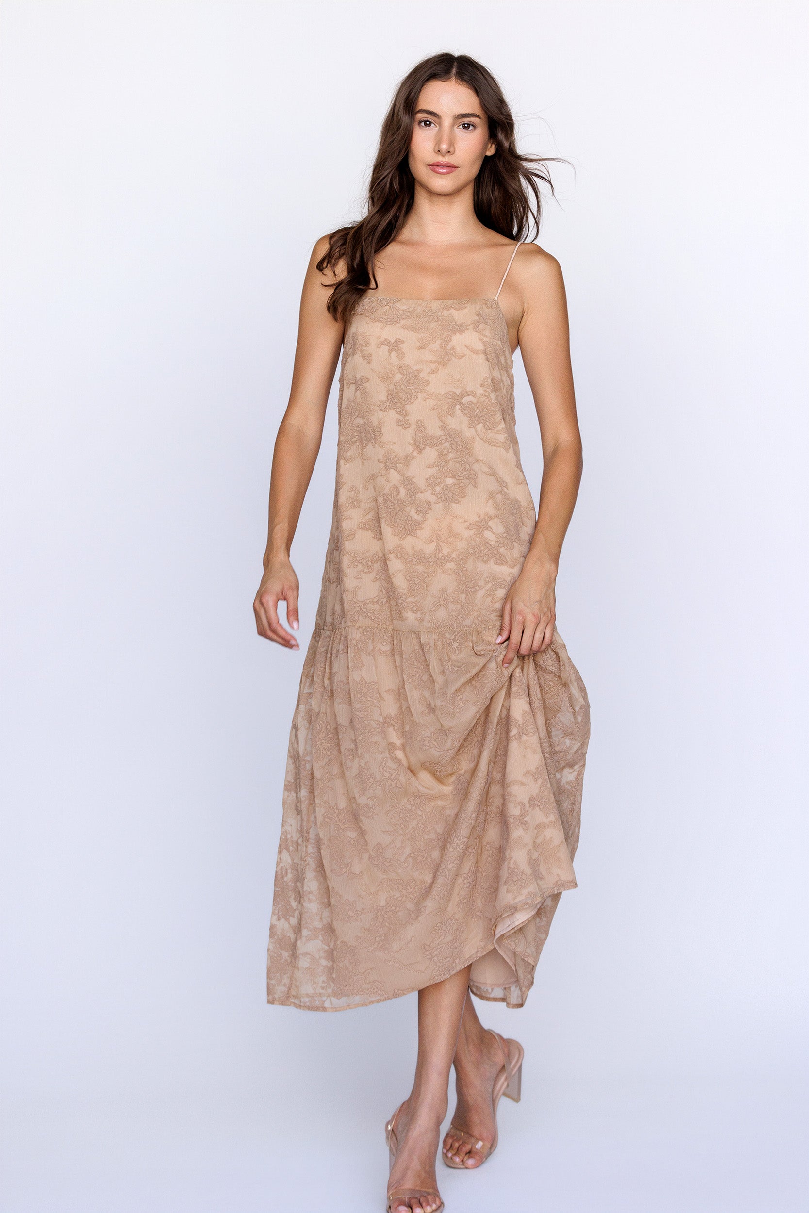 Woman wearing a beige floral textured dress on a white background