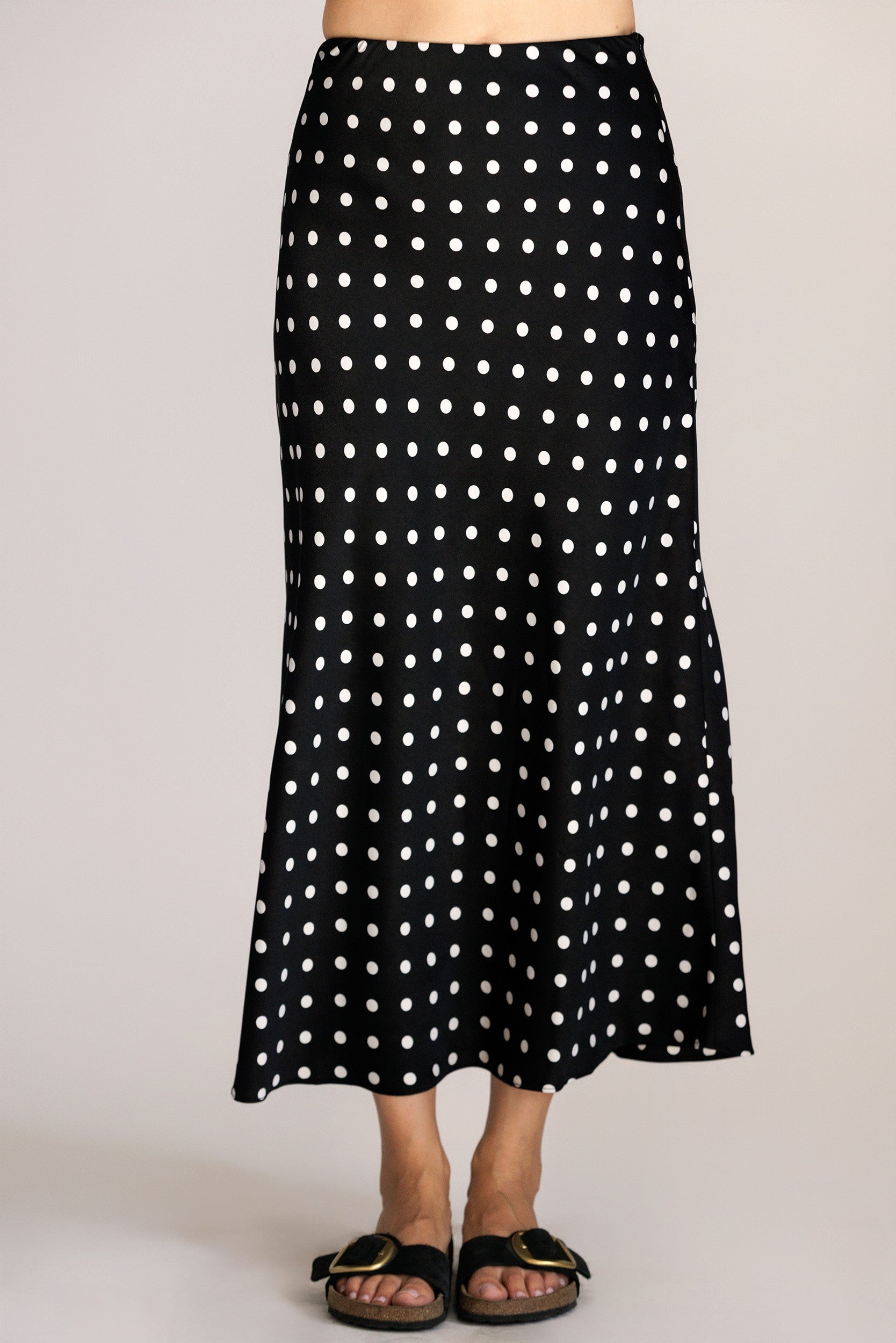 Black polka dot skirt worn by a person on a plain background