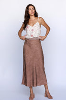 Woman wearing a floral top and brown skirt on a white background