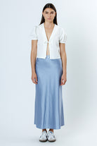 Woman wearing a white blouse and light blue skirt on a white background