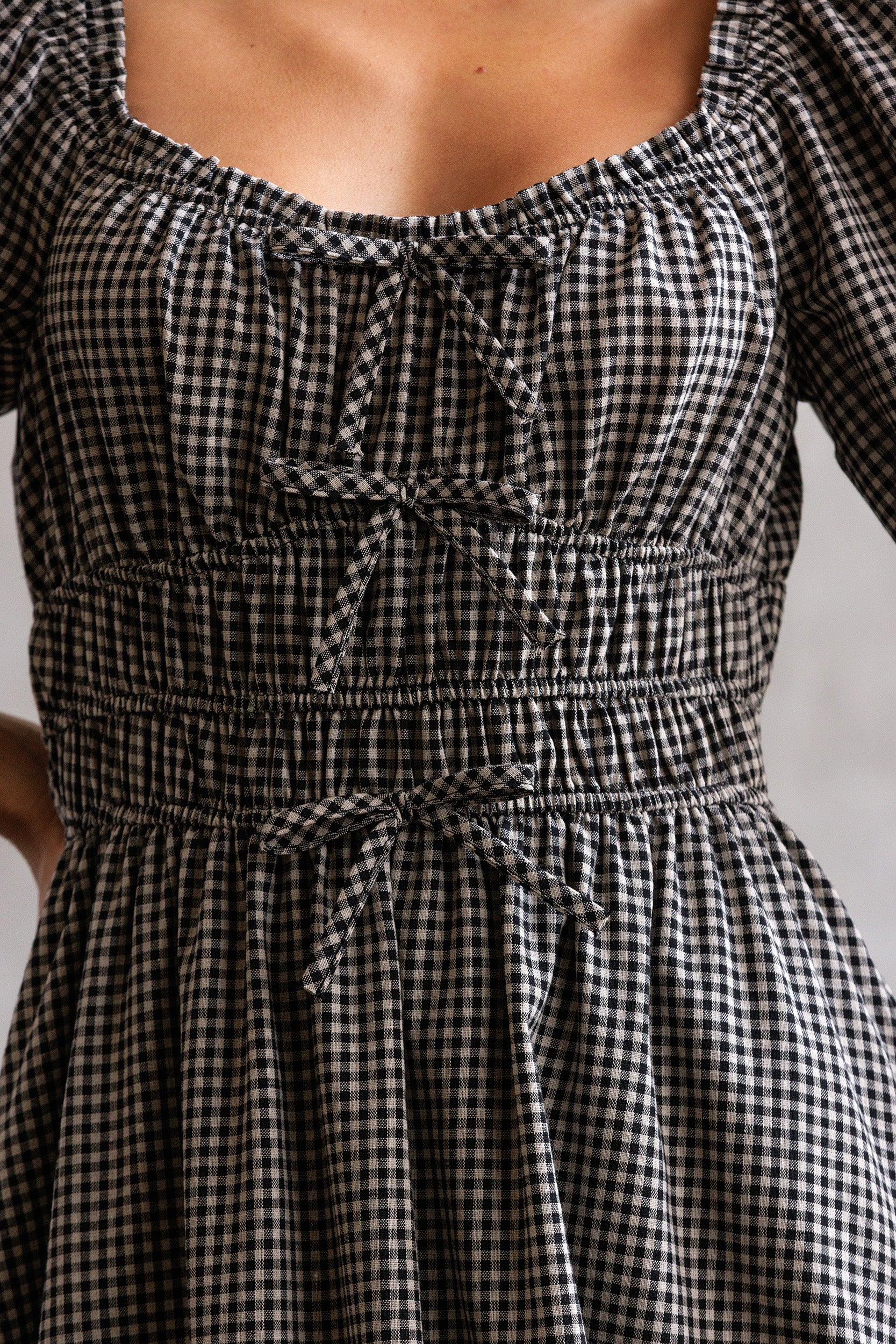 Black and white checkered dress with a tie waist on a neutral background
