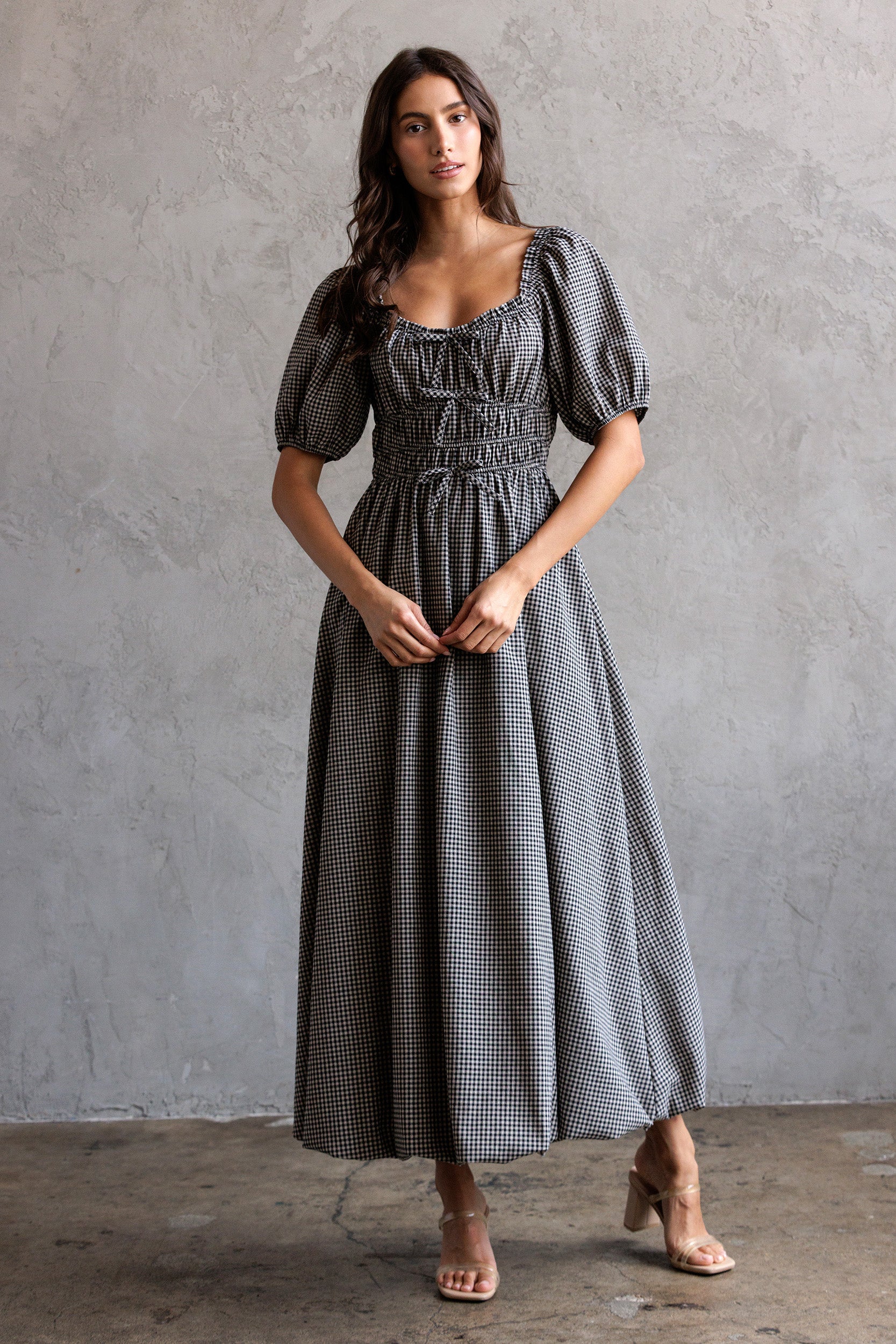 Woman wearing a checkered dress against a gray wall
