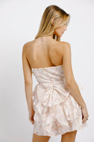 Woman wearing a strapless, ruffled dress on a white background