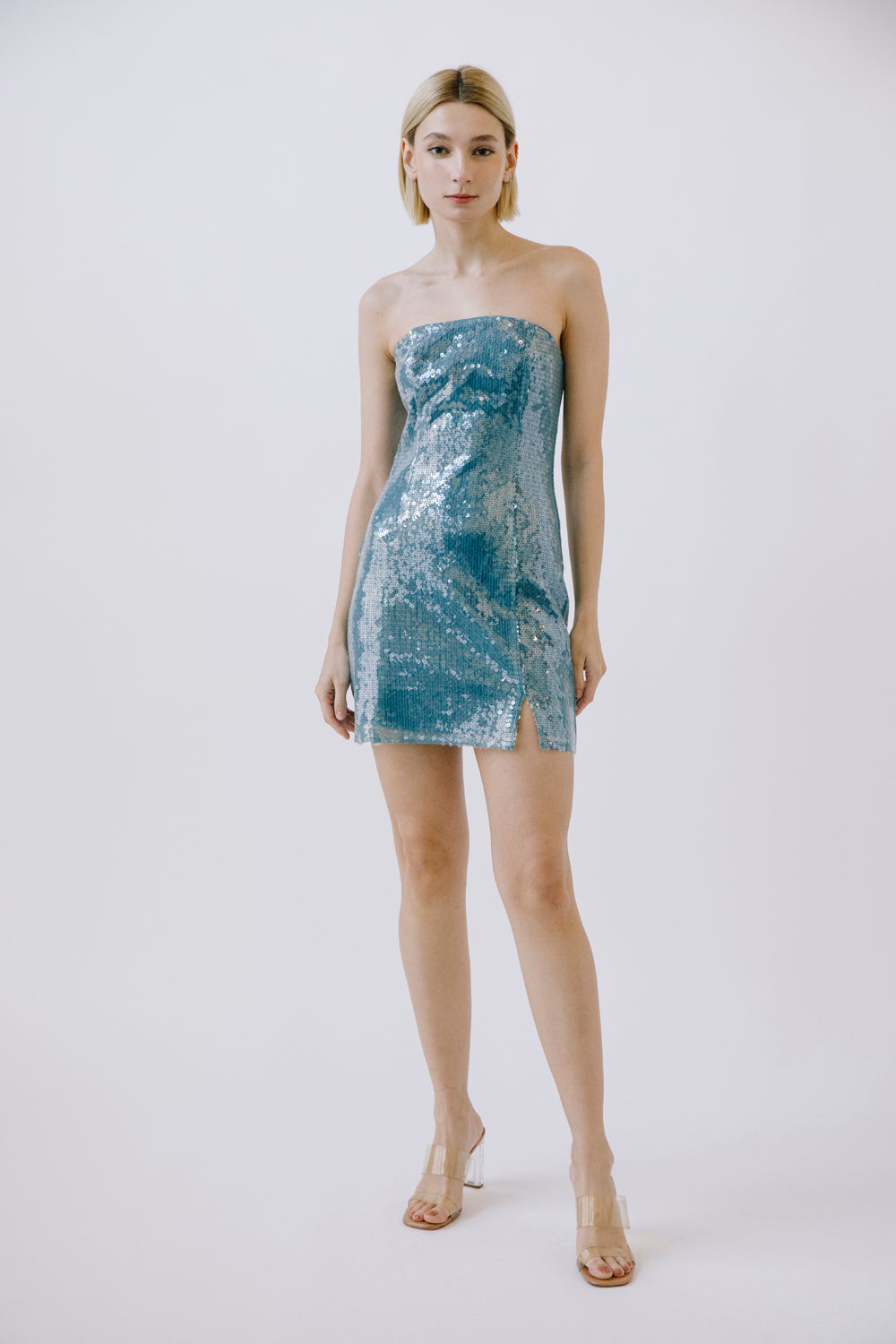 Woman wearing a blue sequin strapless dress and heels on a white background
