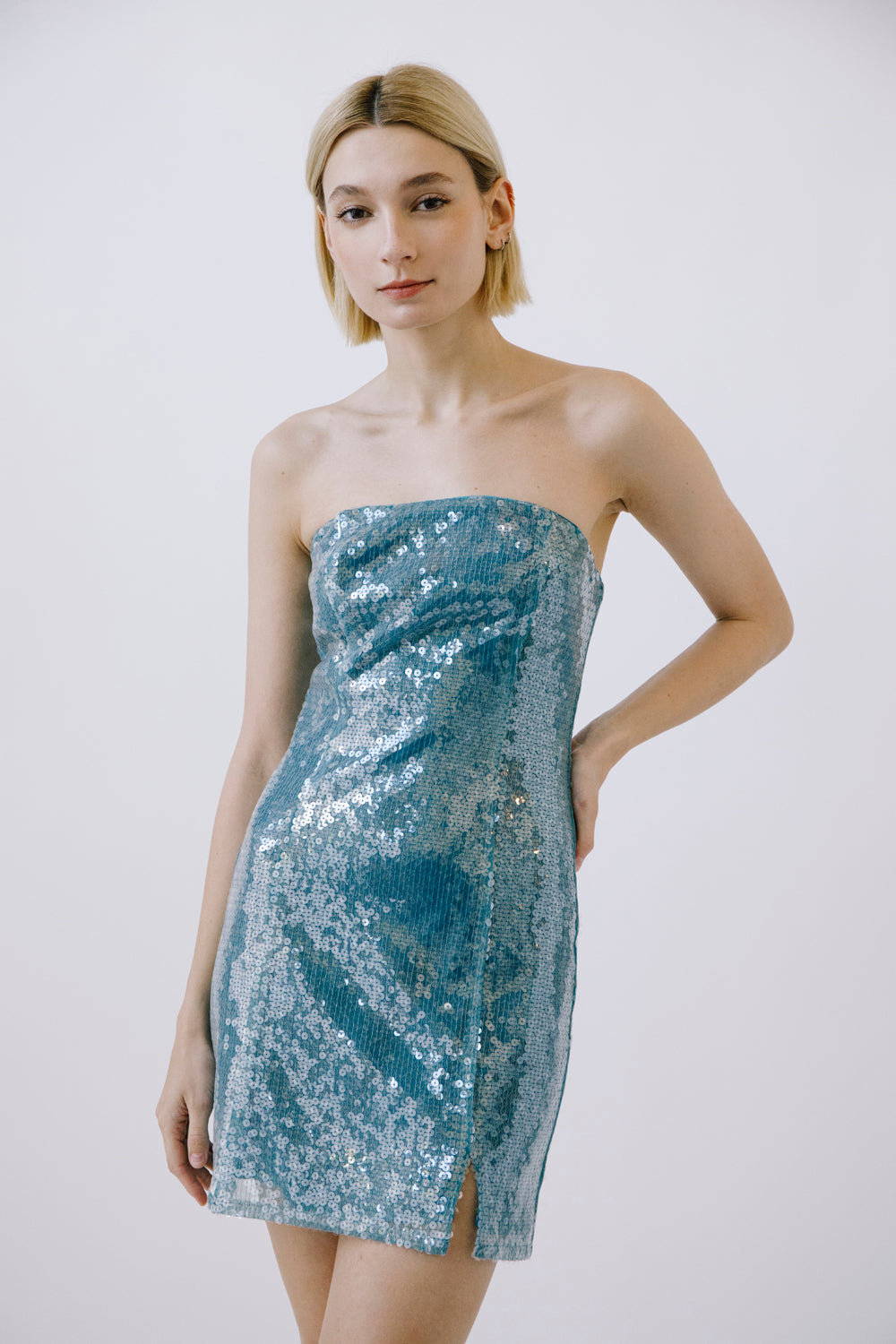 Woman wearing a strapless sequin dress against a plain background