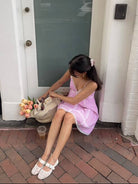 A woman in a pink striped dress sitting on a step outside a building.