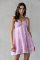 Woman wearing a pink and white striped dress against a gray background