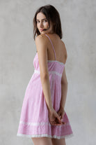 Back view of a woman wearing a pink and white striped dress against a plain background