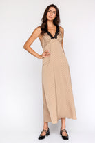 Woman wearing a bronze polka dot dress with black lace details on a white background